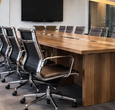 Conference room with a long walnut table and black leather chairs